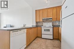 Kitchen featuring wood cabinetry, a white refrigerator, a white electric range, a stainless steel sink, and a white dishwasher - 