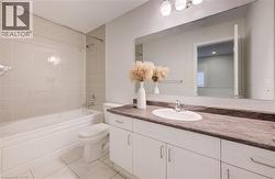Full bathroom with vanity, shower / bath combination, and light tile patterned floors - 