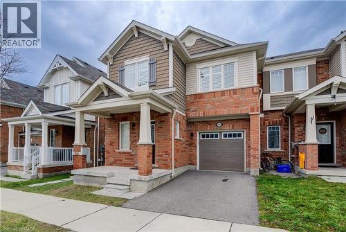 Craftsman house featuring a porch, driveway, brick siding, a garage, and a front yard - 302 Jean Landing, Milton, ON 