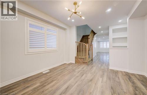 Empty room featuring a chandelier, light wood finished floors, and built in features - 302 Jean Landing, Milton, ON 