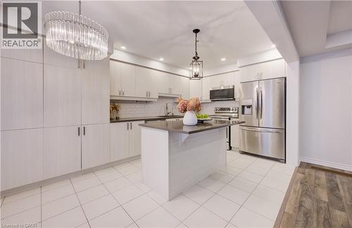 Kitchen featuring stainless steel appliances, a center island, suspended lighting, a kitchen breakfast bar, and light wood-style flooring - 302 Jean Landing, Milton, ON 