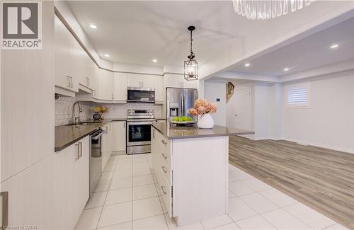 Kitchen with a kitchen island, light tile patterned floors, stainless steel appliances, pendant lighting, and white cabinets - 302 Jean Landing, Milton, ON 