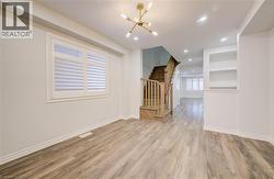 Empty room featuring a chandelier, light wood finished floors, and built in features - 