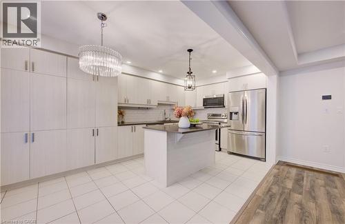 Kitchen with stainless steel appliances, a center island, light wood-style flooring, a kitchen breakfast bar, and suspended lighting - 302 Jean Landing, Milton, ON 