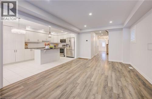 Kitchen with stainless steel appliances, dark countertops, a center island, light wood-style flooring, and open floor plan - 302 Jean Landing, Milton, ON 