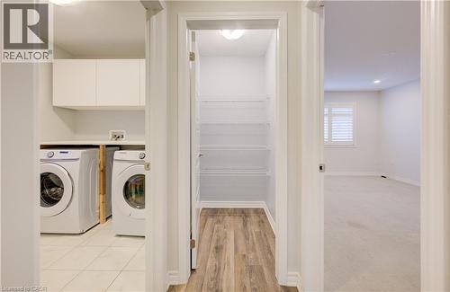 Laundry room with washing machine and dryer, cabinet space, and light wood finished floors - 302 Jean Landing, Milton, ON 
