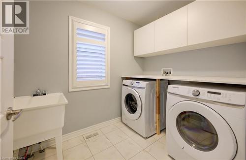 Laundry room with washer and clothes dryer, light tile patterned flooring, and cabinet space - 302 Jean Landing, Milton, ON 