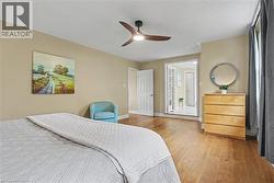 Spacious room featuring wood-finish flooring, a modern ceiling fan with lighting, and neutral wall tones - 