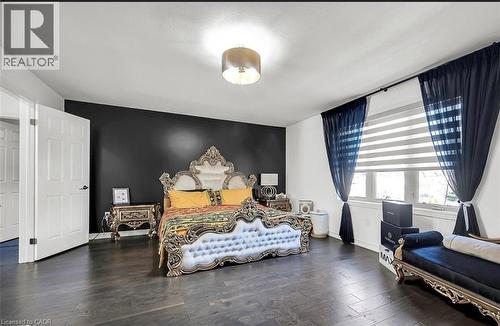 Spacious room featuring dark wood-finish flooring, a prominent black accent wall, and white six-panel doors - 137 Diiorio Circle, Ancaster, ON 
