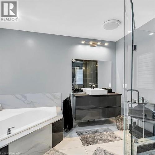Contemporary bathroom featuring a corner soaking tub with a tiled surround, a floating vanity with a vessel sink, a mirrored wall, and a glass-enclosed shower - 137 Diiorio Circle, Ancaster, ON 