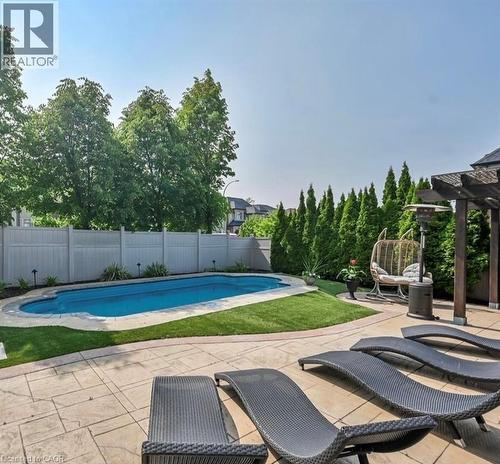 Resort-style backyard featuring a kidney-shaped swimming pool, stamped concrete patio, and a wooden pergola structure - 137 Diiorio Circle, Ancaster, ON 