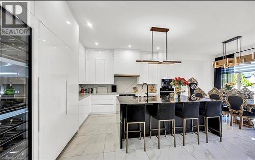 Contemporary kitchen featuring a large black island with seating, white high-gloss cabinetry, and a built-in wine refrigerator - 137 Diiorio Circle, Ancaster, ON 
