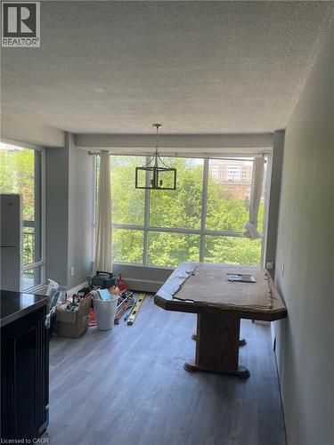 Spacious interior featuring wide-plank wood-finish flooring, a wall of windows, and a contemporary chandelier - 150 Charlton Avenue E Unit# 708, Hamilton, ON 