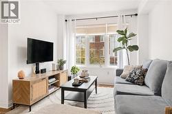 Bright living area featuring a large window, crown molding, and wood-finish flooring - 