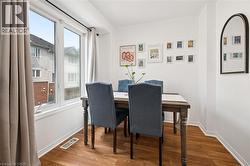 Bright dining area featuring a large double window, wood-finish flooring, white baseboards, and crown molding - 