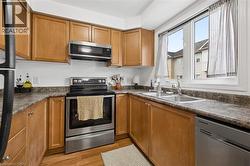 Kitchen featuring wood-finish cabinetry, stainless steel appliances, and a double basin sink - 