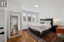 Bedroom featuring wood-finish flooring, white walls, and a modern ceiling light fixture - 