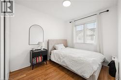 Bright room featuring wood-finish flooring, a contemporary ceiling light fixture, a window with blinds, and white baseboards - 