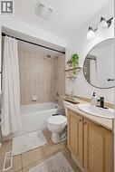 Full bathroom featuring a white tub with shower, tiled surround, and a vanity with a light-toned countertop, oval sink, and black-finish faucet - 