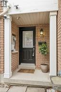 Brick exterior featuring a covered entryway with white support columns, a black front door with a window pane, an exterior wall sconce, and house number ""35"" - 