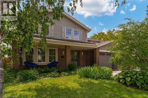 Two-story residence featuring brick and siding facade, covered front porch, and an attached two-car garage - 1320 Monmouth Drive, Burlington, ON 
