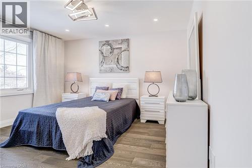 Interior room featuring wood-finish flooring, white walls, and a large window with white trim - 1320 Monmouth Drive, Burlington, ON 