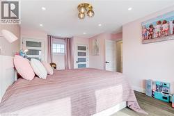 Bedroom featuring recessed lighting, a modern ceiling fixture, wood-finish flooring, and white interior doors with opaque glass panels - 
