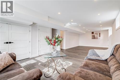 Spacious finished basement featuring wood-finish flooring, recessed lighting, multiple windows, and paneled doors with matte black hardware - 1320 Monmouth Drive, Burlington, ON 