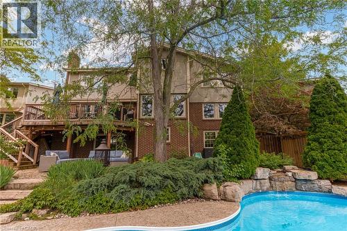 Rear exterior featuring a multi-level deck, a lower patio, and an in-ground pool with a rock waterfall - 1320 Monmouth Drive, Burlington, ON 