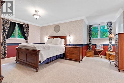 Carpeted bedroom featuring two windows with drapery, detailed crown molding, a decorative ceiling light fixture, and textured wallpaper with a painted lower wall - 110 Grand Ridge Drive, Cambridge, ON 