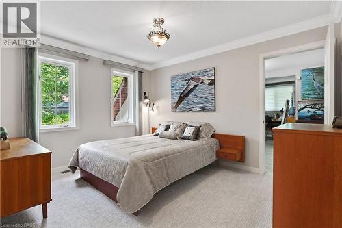 Carpeted bedroom featuring two large windows with exterior views of mature trees, a built-in wall-mounted side table, and recessed lighting - 110 Grand Ridge Drive, Cambridge, ON 
