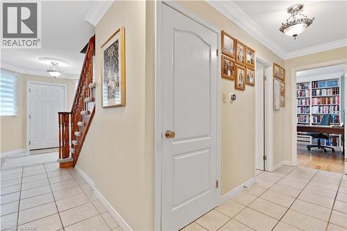 Foyer featuring light-toned tile flooring, crown molding, and a wood staircase with carpeted treads - 110 Grand Ridge Drive, Cambridge, ON 
