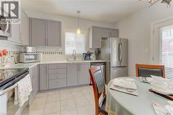 Kitchen featuring gray cabinetry, light countertops, and stainless steel appliances - 