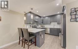 Kitchen featuring dark wood-finish cabinetry, stainless steel appliances, white countertops, and a white tile backsplash - 