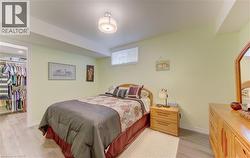 Bedroom featuring a window with blinds, overhead lighting, wood-finish flooring, and a walk-in closet with built-in shelving - 