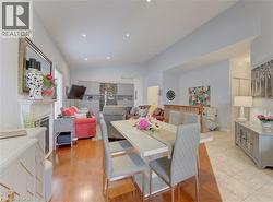 Open-concept living area featuring rich wood-finish flooring, a decorative fireplace with a mantel, recessed lighting, and a dining area with a modern table and chairs - 