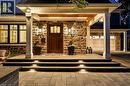 Stone facade entry with a wood front door, covered porch, integrated step lighting, and an attached two-car garage - 336 Newbold Court, Burlington, ON 