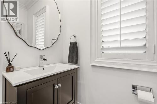 Dark wood vanity with a white integrated sink, polished chrome faucet, and an organic-shaped mirror - 336 Newbold Court, Burlington, ON 