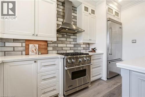 Stainless steel range with matching hood vent, subway tile backsplash, white shaker cabinetry with brushed nickel hardware, and wood-finish flooring - 336 Newbold Court, Burlington, ON 