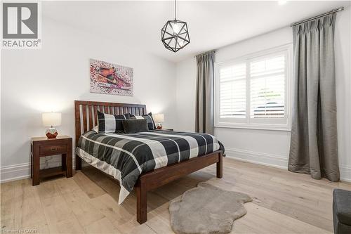 Bedroom featuring light wood-finish flooring, white walls, and a window with plantation shutters - 336 Newbold Court, Burlington, ON 
