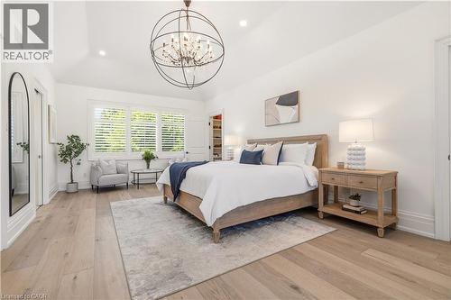 Spacious room featuring vaulted ceilings, wide plank wood-finish flooring, a contemporary chandelier, large windows with plantation shutters, and a built-in closet with shelving - 336 Newbold Court, Burlington, ON 