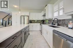 Contemporary kitchen featuring a large island with dark wood-finish cabinetry, light stone countertops, stainless steel appliances, and a dark stone backsplash - 