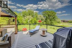 Spacious outdoor deck featuring composite decking, glass railing, and a dark metal pergola with string lighting - 