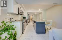 Kitchen featuring white cabinetry, stainless steel appliances, subway tile backsplash, and a large island with a stone countertop - 