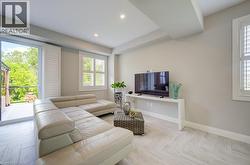 Spacious living area featuring light-toned walls, recessed lighting, and wood-finish flooring laid in a herringbone pattern - 