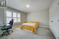 Bedroom featuring light gray wall paint, gray carpeting, and white baseboards - 