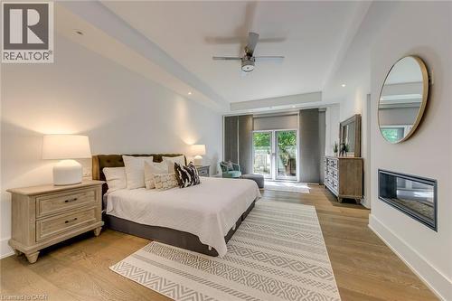 Spacious room featuring wood-finish flooring, a contemporary ceiling fan, recessed lighting, and a modern wall-mounted fireplace - 2104 Devon Road, Oakville, ON - Indoor Photo Showing Bedroom
