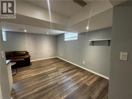 Spacious room featuring wood-finish flooring, recessed lighting, and a textured accent wall - 13 Sorrento Street, Kitchener, ON - Indoor