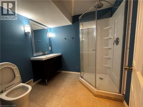 Spacious bathroom featuring a corner shower enclosure, modern vanity with integrated sink, decorative framed mirror, and wall-mounted sconces - 13 Sorrento Street, Kitchener, ON - Indoor Photo Showing Bathroom