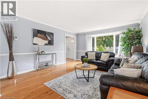 Living area featuring wood-finish flooring, light blue walls with white trim, and a prominent bay window - 4277 Longmoor Drive, Burlington, ON 